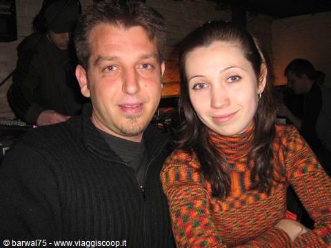 Smiling couple in a dim pub, she wears an orange green sweater