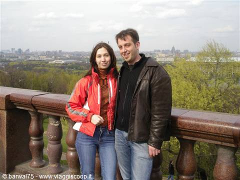 Couple in jackets beside granite balustrade, Moscow skyline behind