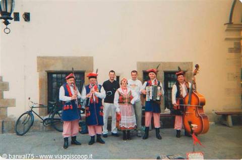 Folk musicians in traditional costume with clarinet, accordion and double bass, posing with tourists