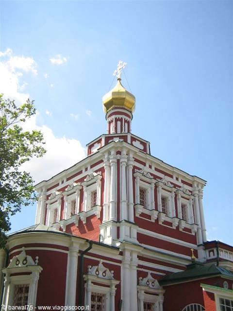Red and white church with golden onion dome against blue sky