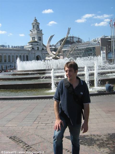 Man in front of the fountain and Kiev railway station under sunny sky