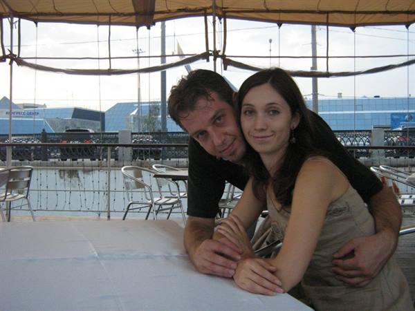 Man embraces smiling woman at a table on an outdoor terrace