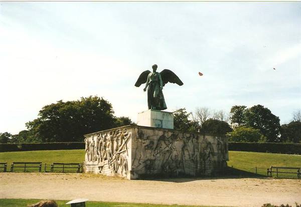 Bronze winged statue on carved stone relief base in a park