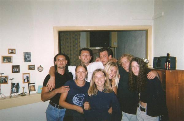 Group of young friends posing together in a room with photos on the wall