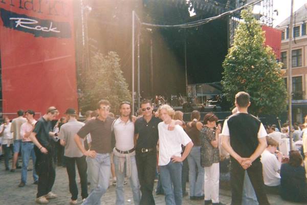 Four friends pose in front of an open-air concert stage