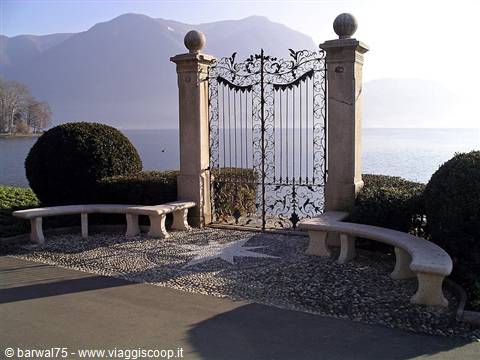 Wrought iron gate between stone pillars, curved benches and lake