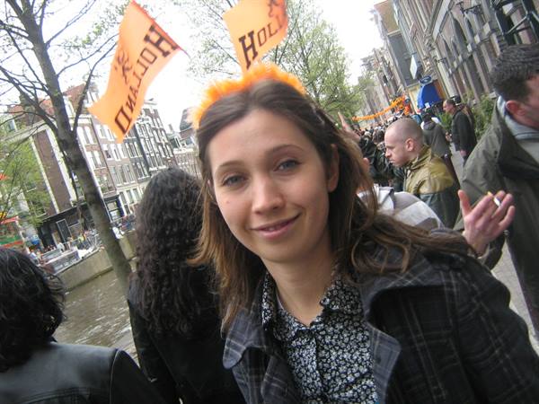 Girl wearing orange feather headdress among Holland flags along Amsterdam canals