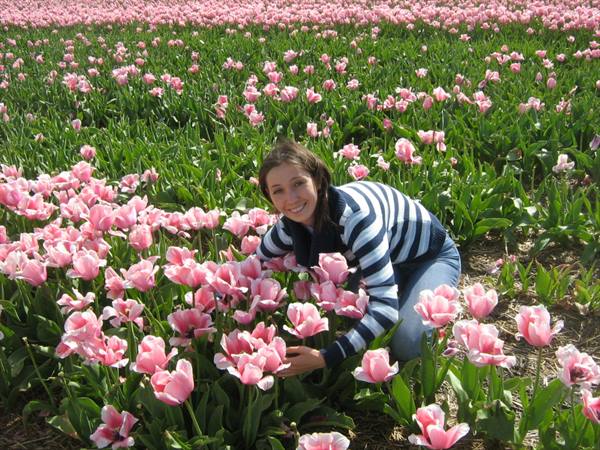 Woman crouching among blooming pink tulips in sunlight