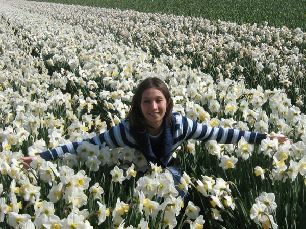 Girl among a field of blooming white daffodils in the sun