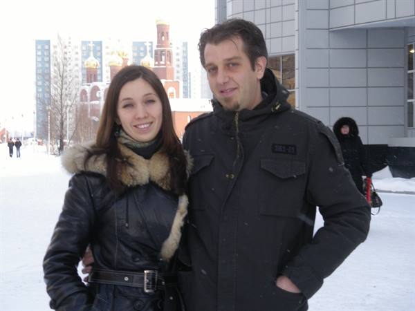 Smiling couple in winter, red church with golden domes behind