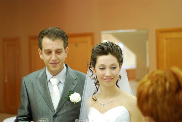 Bride in white gown with veil and groom in gray suit indoors