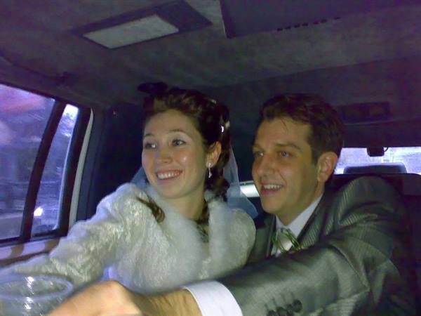 Veiled bride and groom in gray suit smiling inside a car