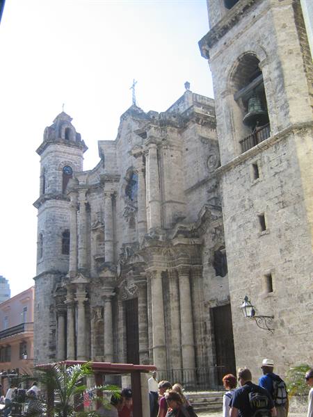 Tourists before Havana Cathedral, baroque stone facade in daylight
