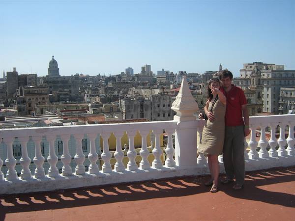 Couple on white balustrade terrace, Havana skyline and Capitolio behind