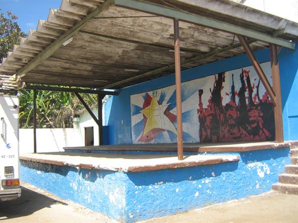 open blue stage with red mural and star, van parked nearby