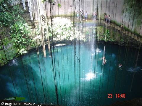 Swimmers in turquoise cenote Ik Kil water, roots and vines hanging from walls