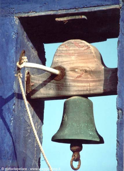 Green bronze bell hanging from a wooden beam under a blue frame