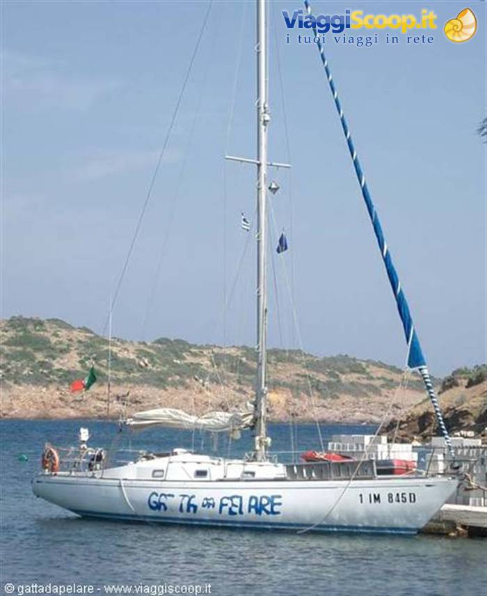 White sailing yacht moored at the dock, rocky Mediterranean coastline behind