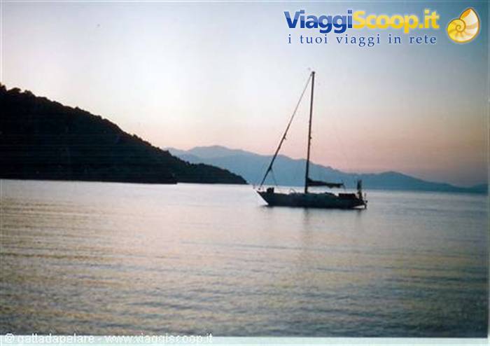 Sailboat anchored in a bay at dusk, dark mountains behind