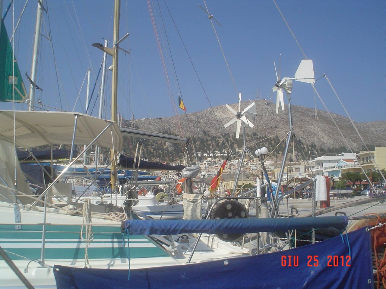 Sailboats moored in the harbor, wind generators on masts, arid mountains behind