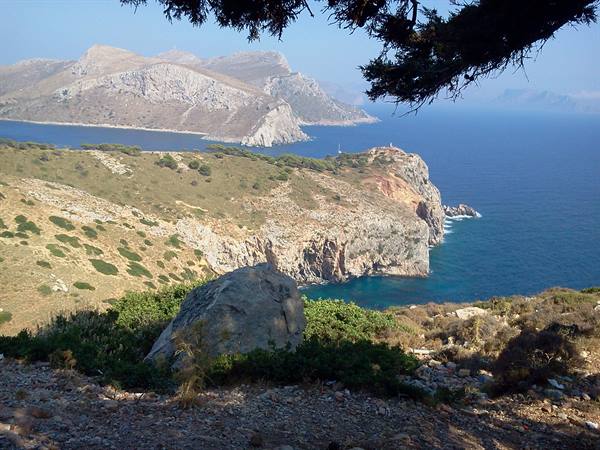 Rocky cliffs over the sea at Cap de Creus, Mediterranean shrubs and blue mountains