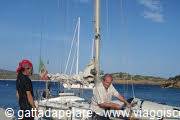 Man at the helm and woman in red hat aboard a sailboat