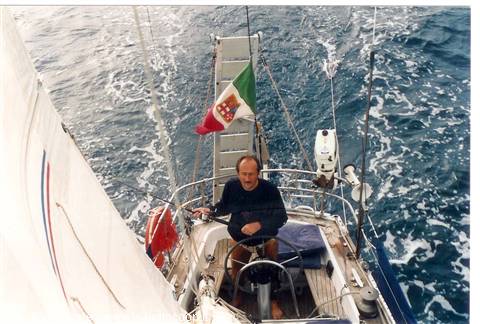 Man at the helm of a sailboat, Italian flag, open sea