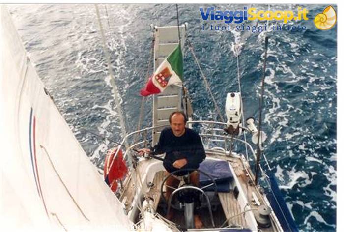 Man at the helm of a sailboat, Italian flag, open sea
