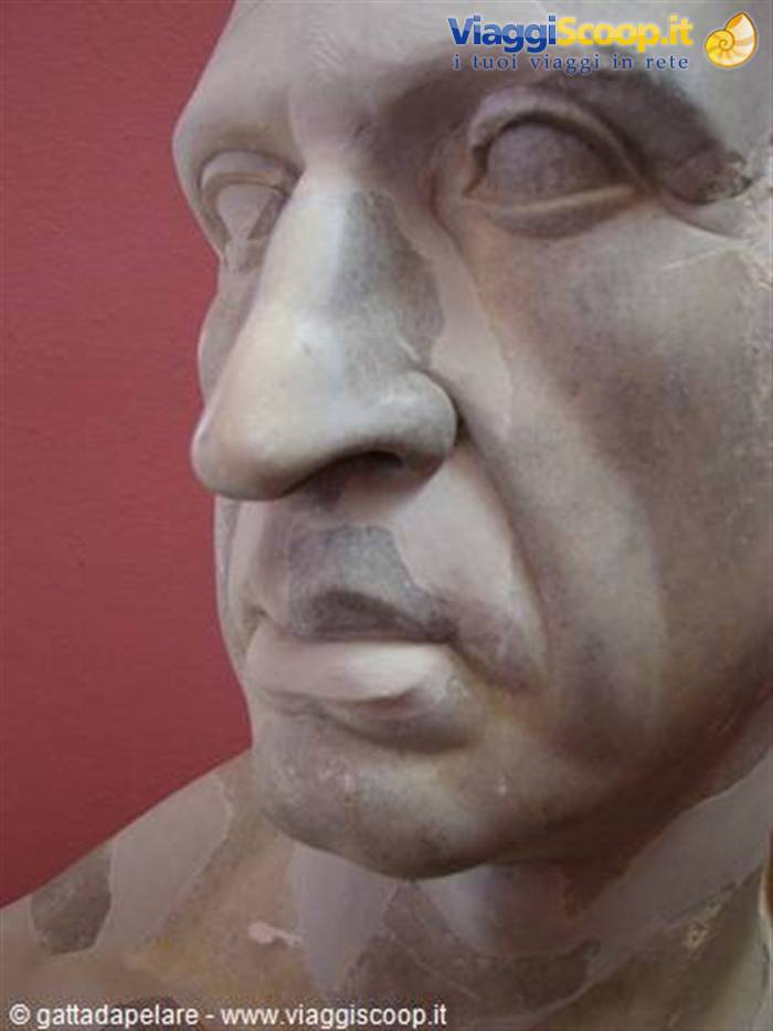 Marble face of ancient Roman statue against red background