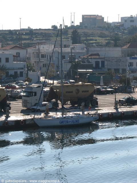 Sailing boat moored at the harbor, white houses and tanker trucks behind