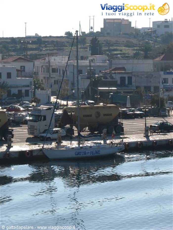 Sailing boat moored at the harbor, white houses and tanker trucks behind