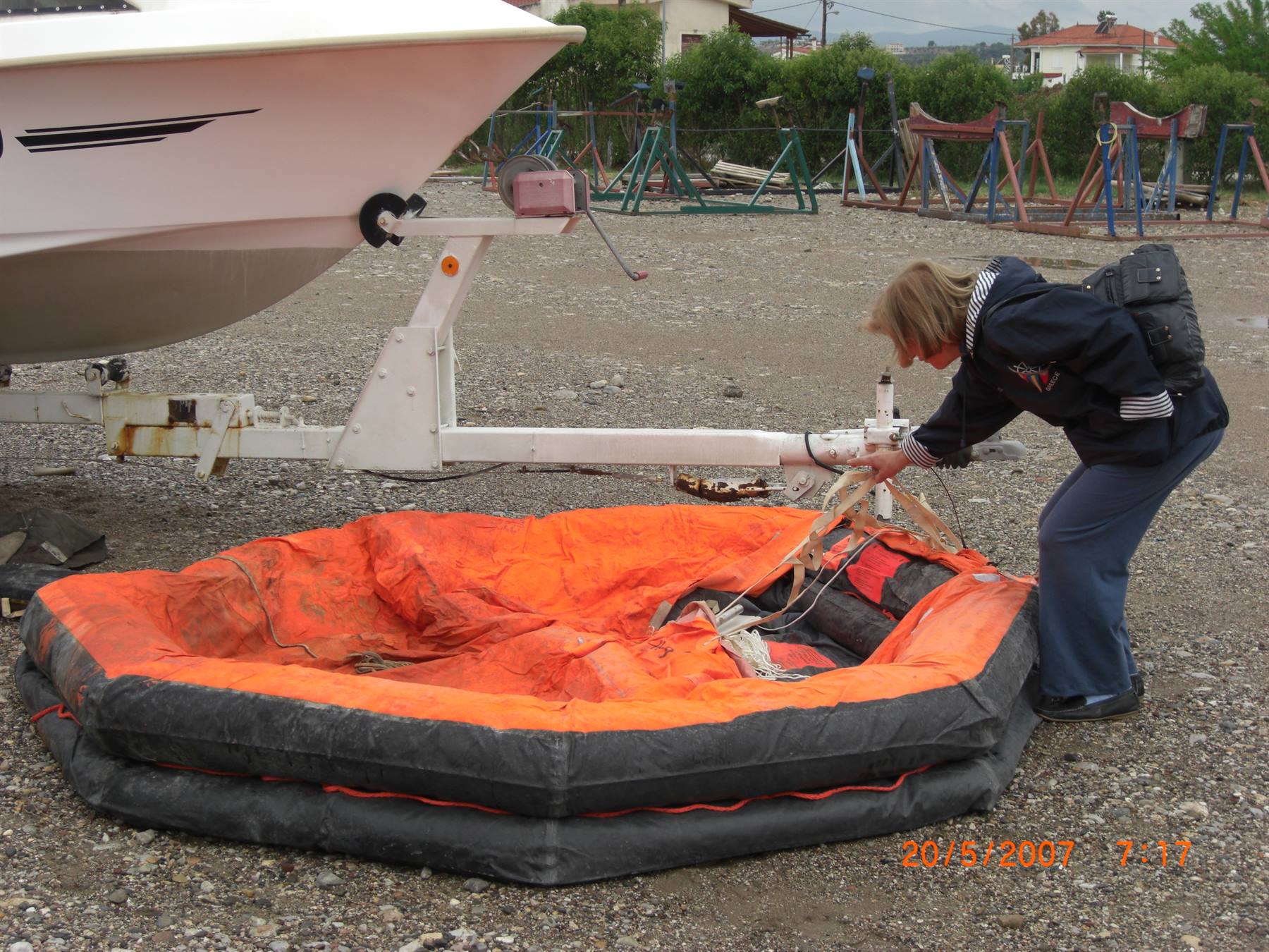 Woman inflates an orange life raft next to a boat on a trailer