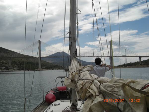 Rio-Antirrio bridge seen from a sailboat deck, sailor handling sails