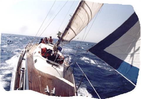 Crew sailing a yacht in choppy sea, spinnaker flying