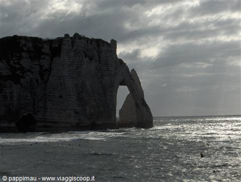 Limestone cliff with natural sea arch under cloudy sky, Étretat