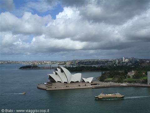The Sydney Opera House with white sails overlooks the harbour, a ferry passing by