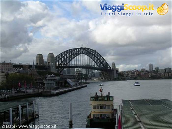 Ferry at the dock in front of Sydney Harbour Bridge under clouds