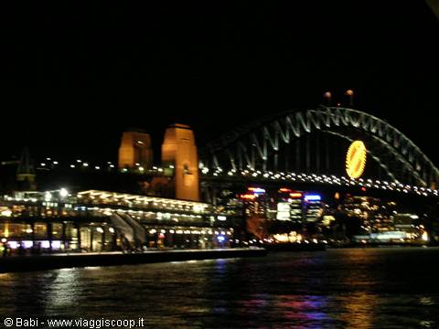 Sydney Harbour Bridge lit at night with full moon above the lights