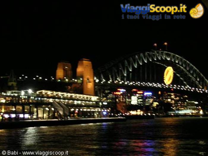 Sydney Harbour Bridge lit at night with full moon above the lights