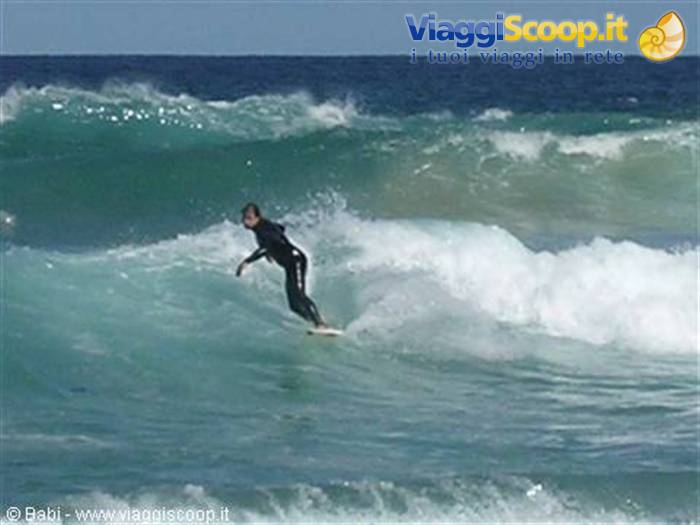Surfer in black wetsuit riding a green wave at Babi beach