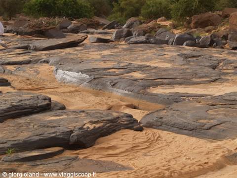 Smooth black rocks and golden sand in a dry riverbed