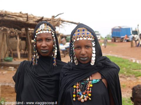 Women in black with beaded headdresses and silver discs in a village