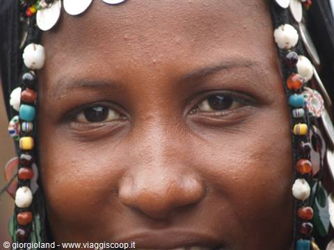 Portrait of a woman with hair adorned with colorful beads and white shells