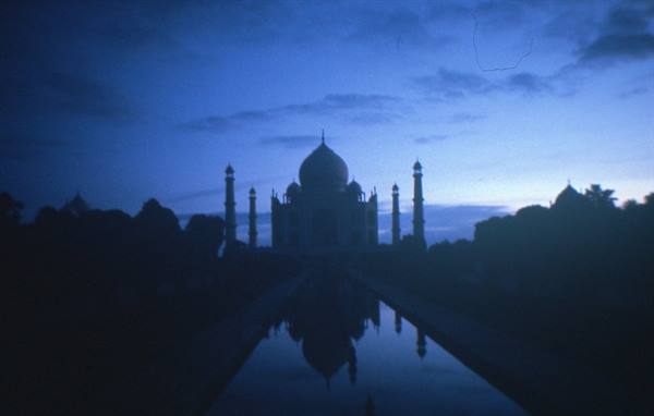 Taj Mahal silhouetted at dusk, dome and minarets reflected in the water channel