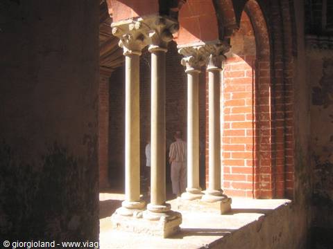 Stone columns with carved capitals in the cloister, red bricks, sunlight
