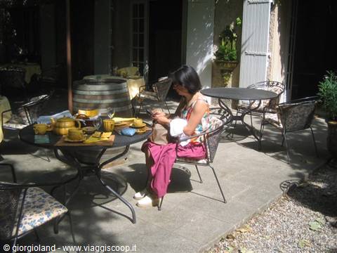Woman seated at courtyard table with wine barrel and yellow ceramics