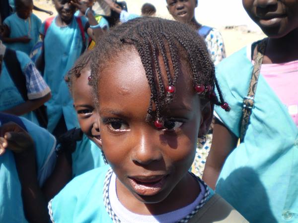 Girl with beaded braids among schoolmates in light blue uniforms