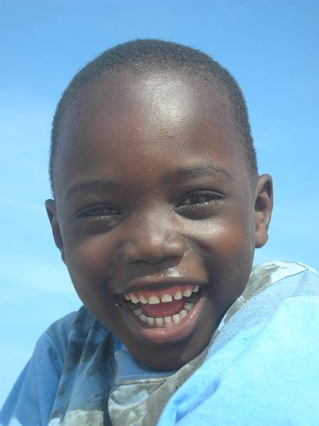 Smiling child in a blue shirt, clear sky behind him