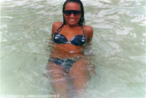 Woman in black bikini and sunglasses in clear turquoise water