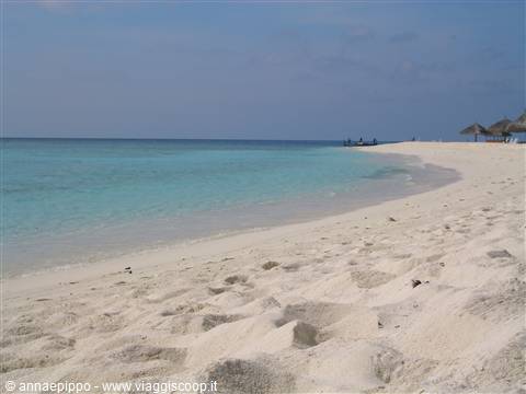 White sand and turquoise water, thatched umbrellas along the Maldivian shore